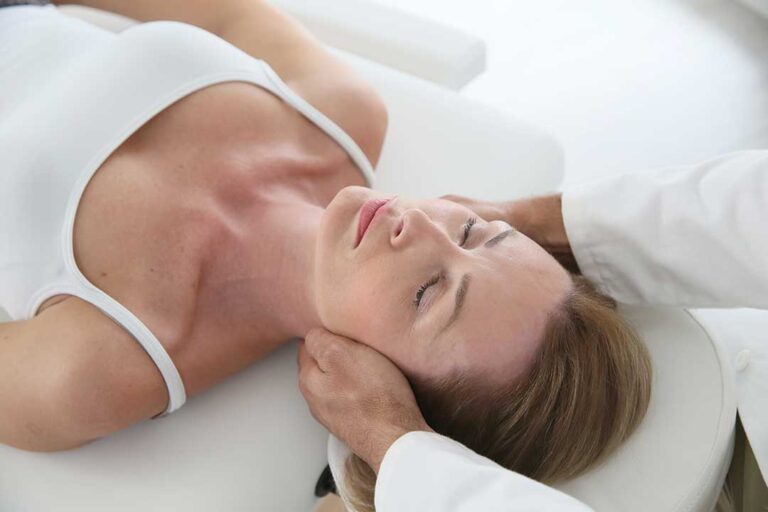 A pregnant woman receives a gentle chiropractic adjustment while lying on a special cushioned table.