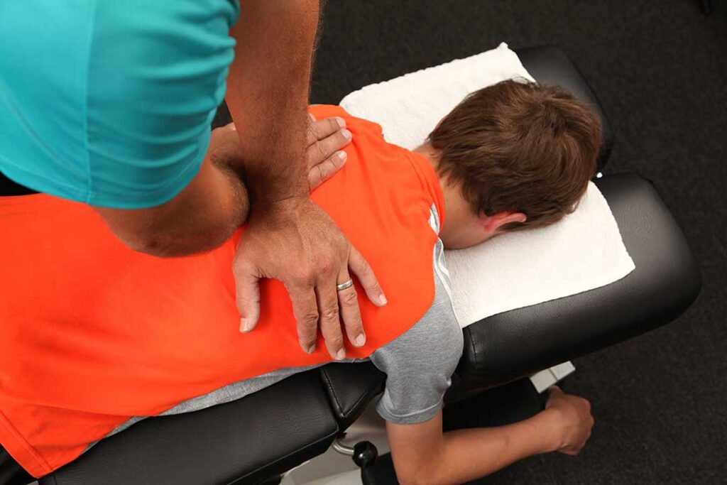 A person gently stretching their shoulder indoors while looking concerned about a popping sensation.
