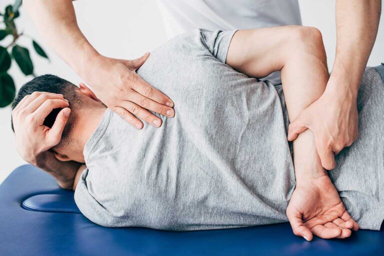 A chiropractor discusses health concerns and treatment options with a patient in a comfortable medical office.